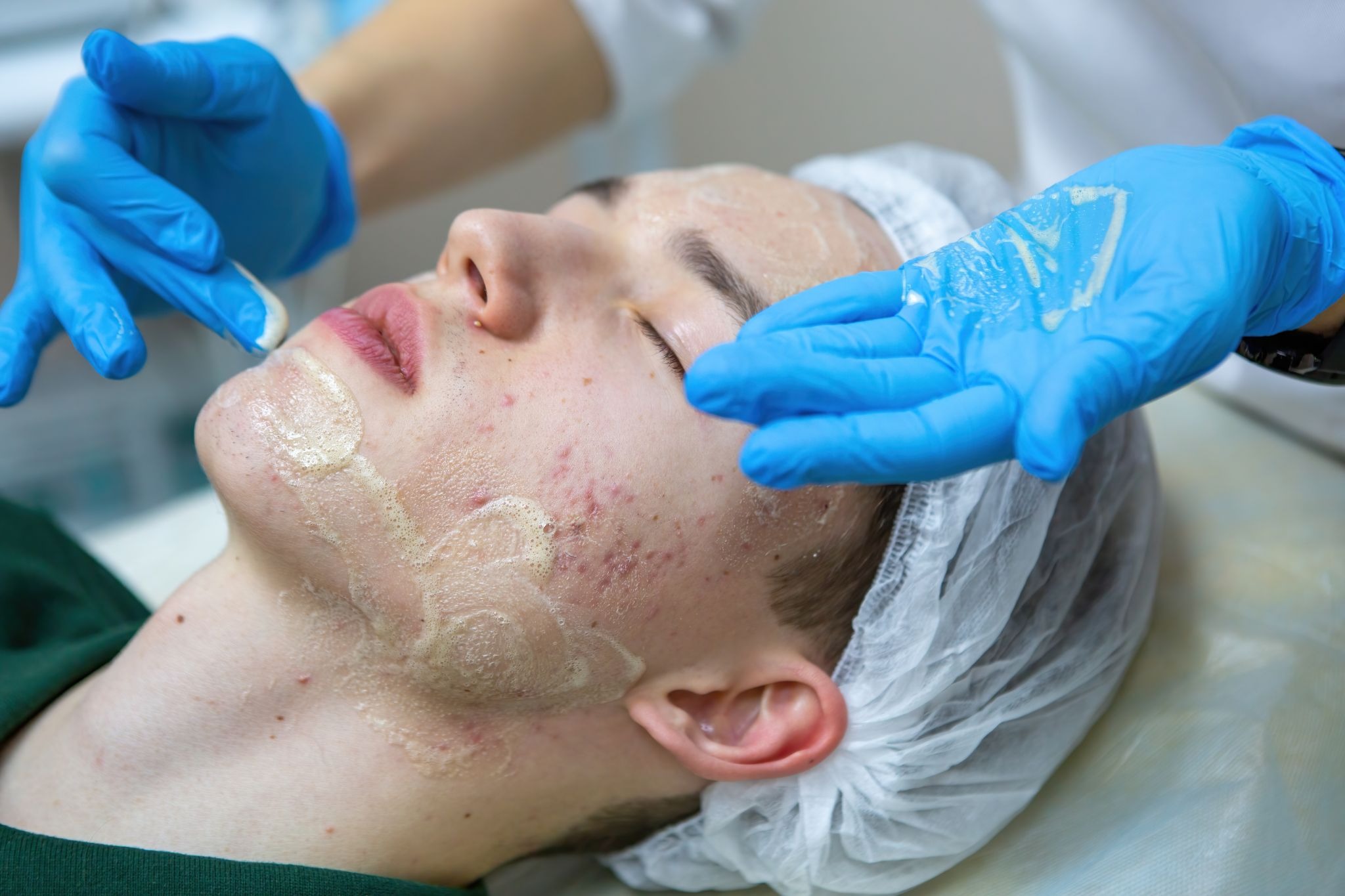 Man receiving a facial treatment from a skincare professional wearing blue gloves at a med spa