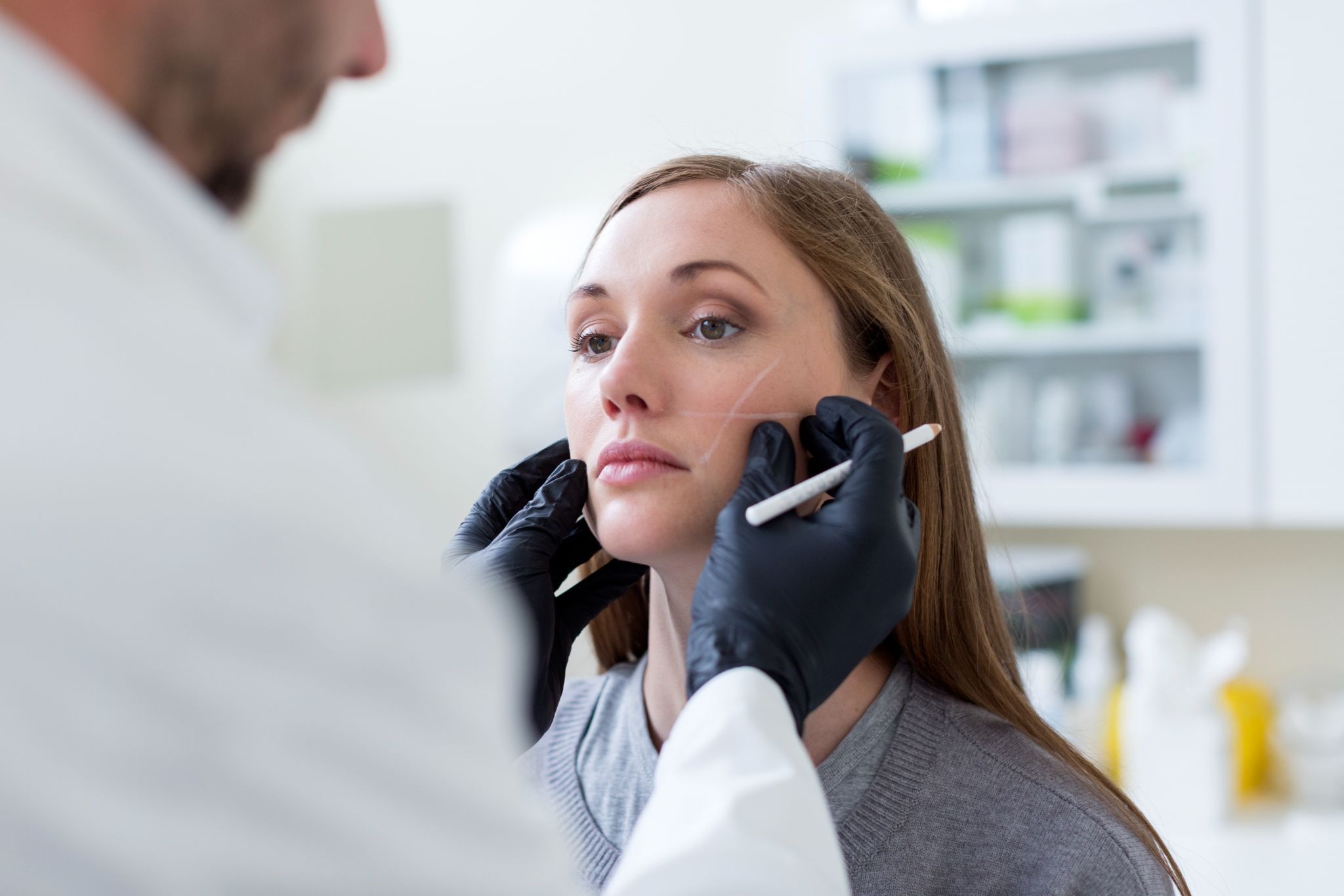 Aesthetic provider evaluating a woman's face before dermal filler injections