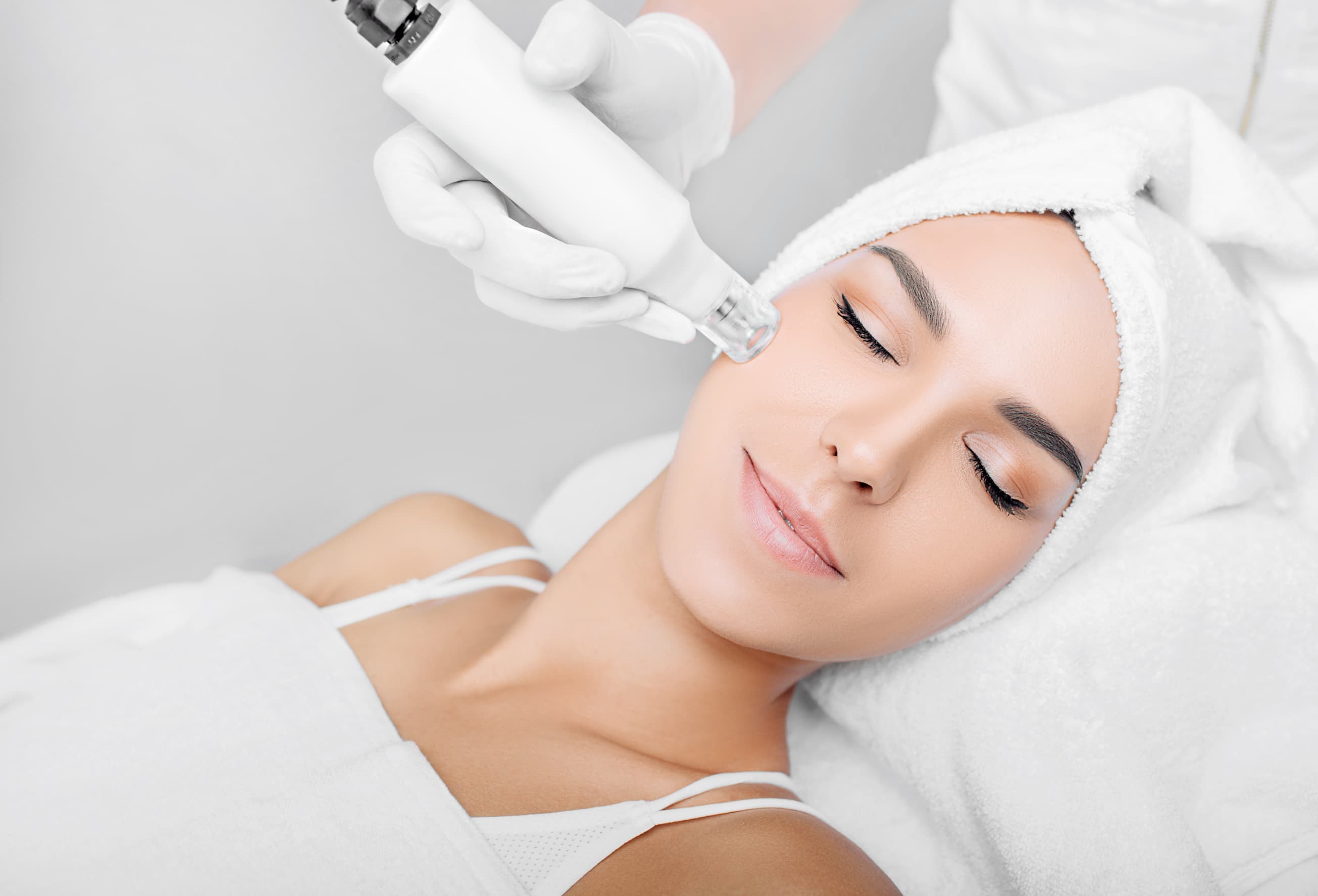 Woman relaxing during a professional microneedling treatment in a bright spa room