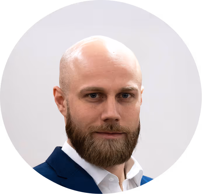 Portrait of a bald man with a full beard wearing a blue suit jacket and white shirt.