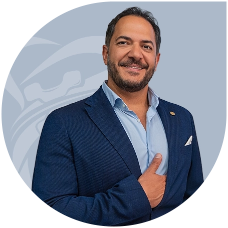Smiling Dr. Hessam Rahimi with short hair and beard wearing a blue suit jacket and light blue shirt, giving a thumbs up.