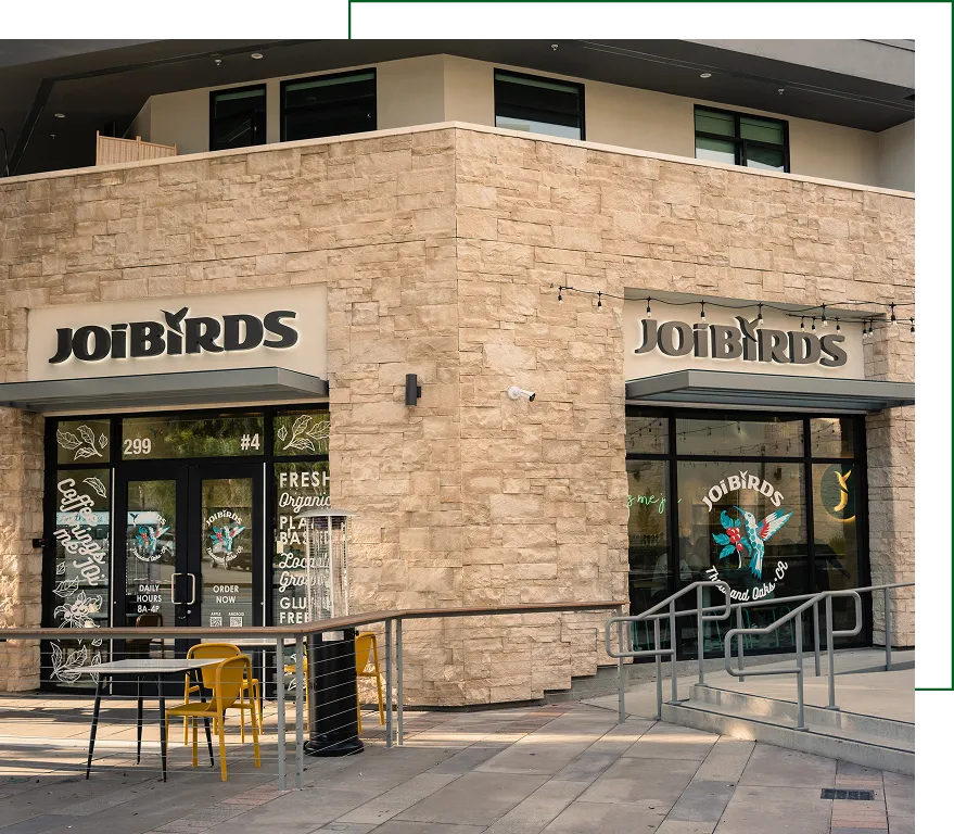 Exterior promotional signage for JoiBirds café with branded window graphics and logo