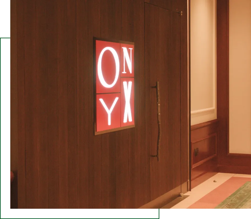 Indoor illuminated ONYX brand sign mounted on a dark wooden wall near store entrance