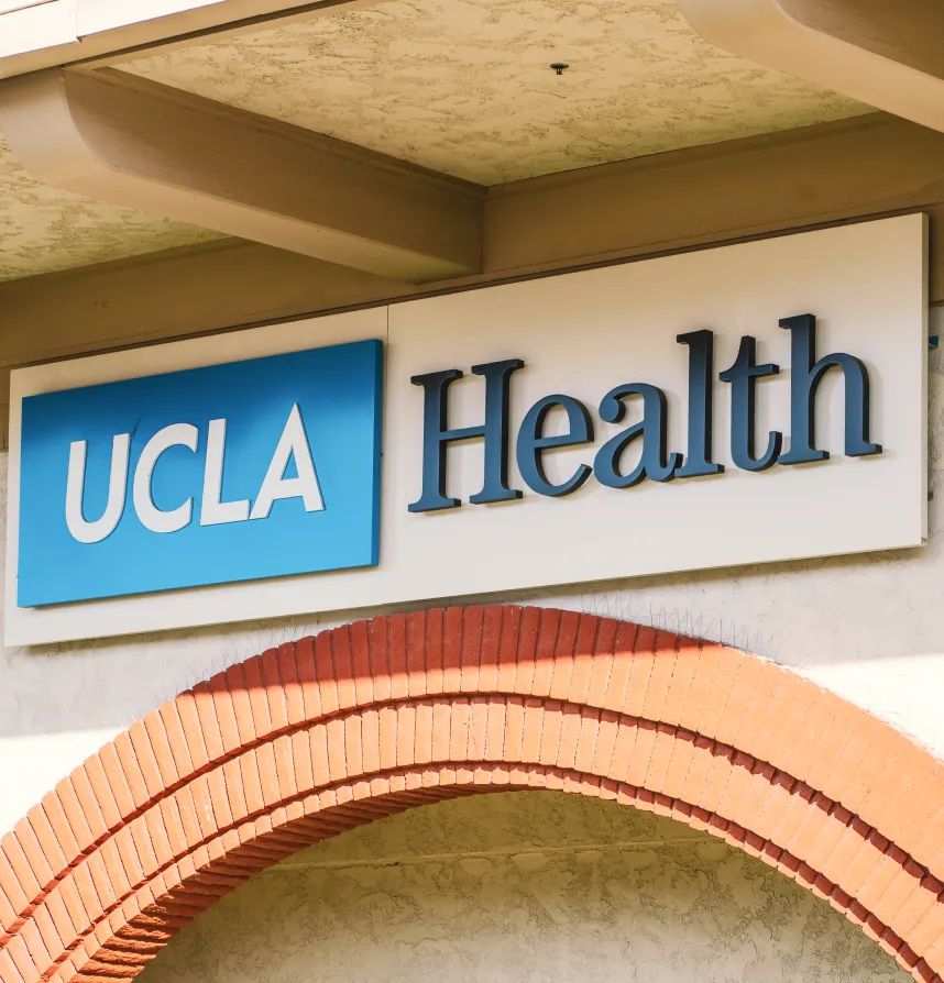 UCLA Health building sign mounted above entrance with red brick arch below