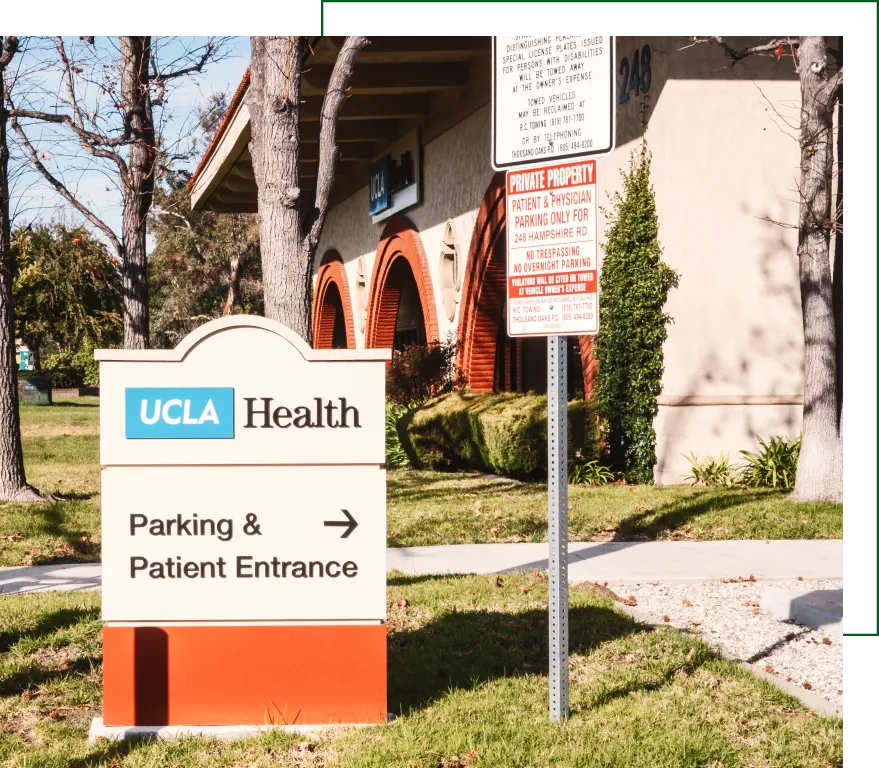 UCLA Health parking and patient entrance sign outside medical building with red arch and directional arrow