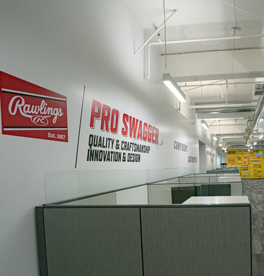 Corporate office wall signage featuring Rawlings and Pro Swagger branding above cubicles in modern workspace