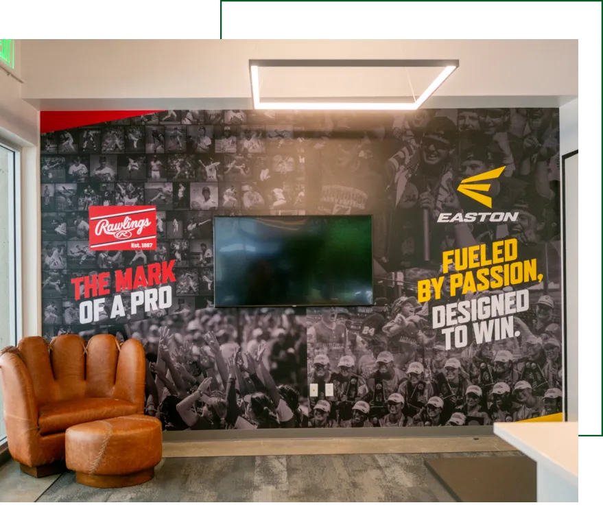 Office wall mural with motivational branding for Rawlings and Easton featuring black-and-white crowd imagery and a mounted TV