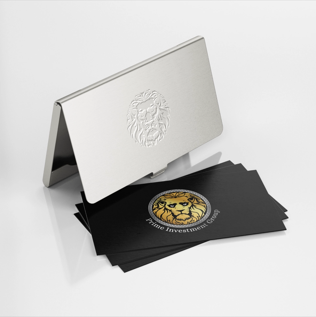 Metalowa wizytówka z grawerem głowy lwa obok stosu czarnych wizytówek z logo lwa i napisem Prime Investment Group.