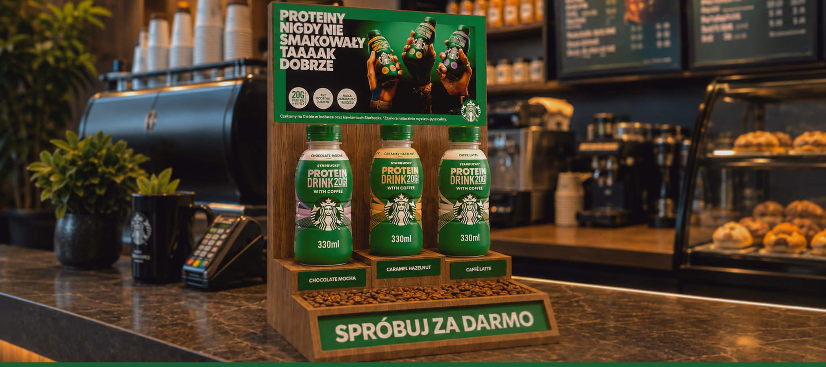 Trzy butelki białkowego napoju Starbucks z kawą na ladzie kawiarni, smak czekoladowy, karmel, latte.