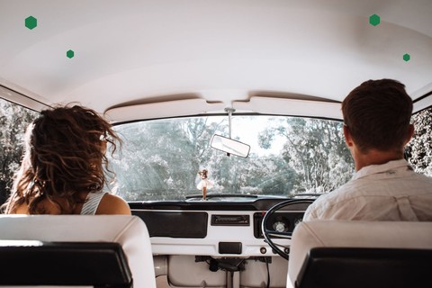 Couple sitting side by side in the front seats of a car, seen from behind