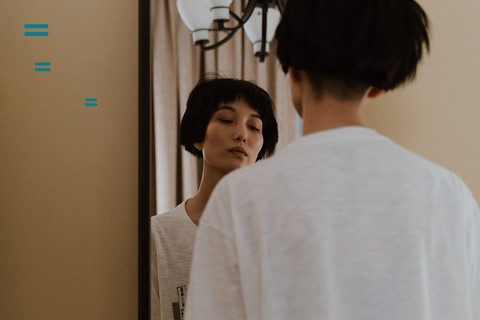 Woman looking at her own reflection in a full-length mirror