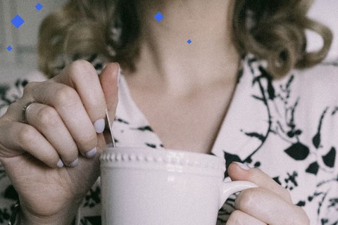Woman's hands holding a mug in the early morning, stirring a hot drink