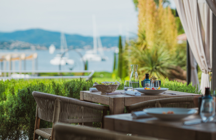 Terrasse de restaurant Kube Saint-Tropez avec vue sur mer, voiliers et plats gastronomiques en bord de Méditerranée.