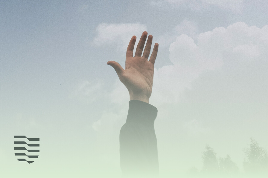 Raised hand against a soft cloudy sky