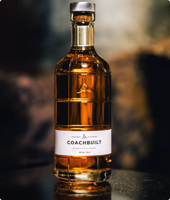 Bottle of Coachbuilt blended Scotch whisky with amber liquid, featuring a white label and cork stopper.