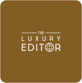 The Luxury Editor logo with a globe inside the letter O on a brown background.