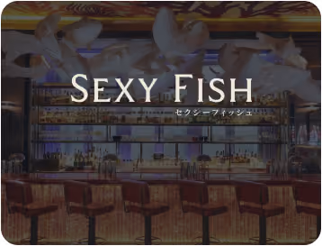 Bar interior with wooden stools and illuminated shelves filled with bottles, overlaid with text 'SEXY FISH'.