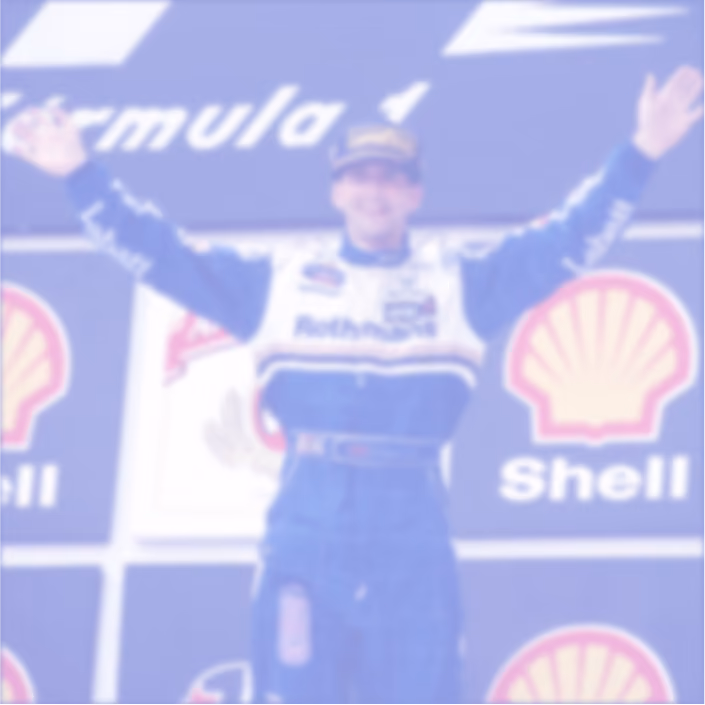 Race car driver celebrating on a Formula 1 podium with arms raised, wearing a blue and white racing suit and cap, Shell logos in the background.