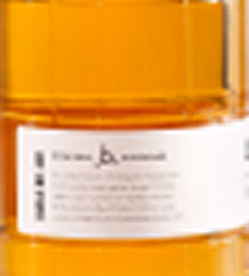 Close-up of a white label with small unreadable text on an orange translucent container.
