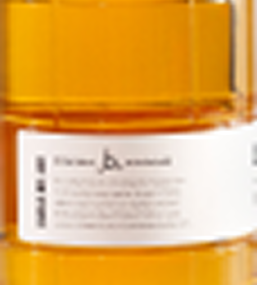 Close-up of a white label with small unreadable text on an orange translucent container.