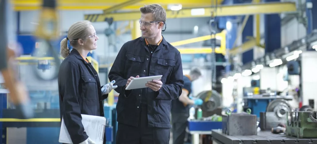 Two factory workers discuss the Gemba