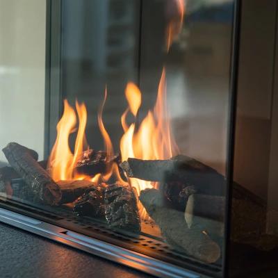 Gas fireplace with ceramic logs burning, showing proper flame operation during repair service.