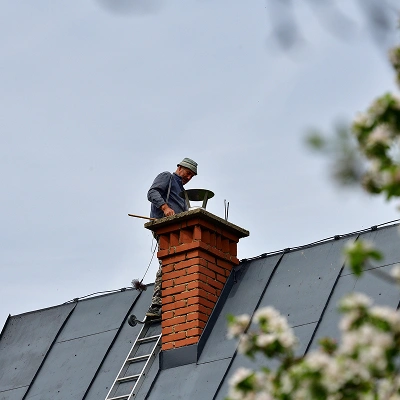 Technician inspecting a chimney on a rooftop to assess safety and structural condition.