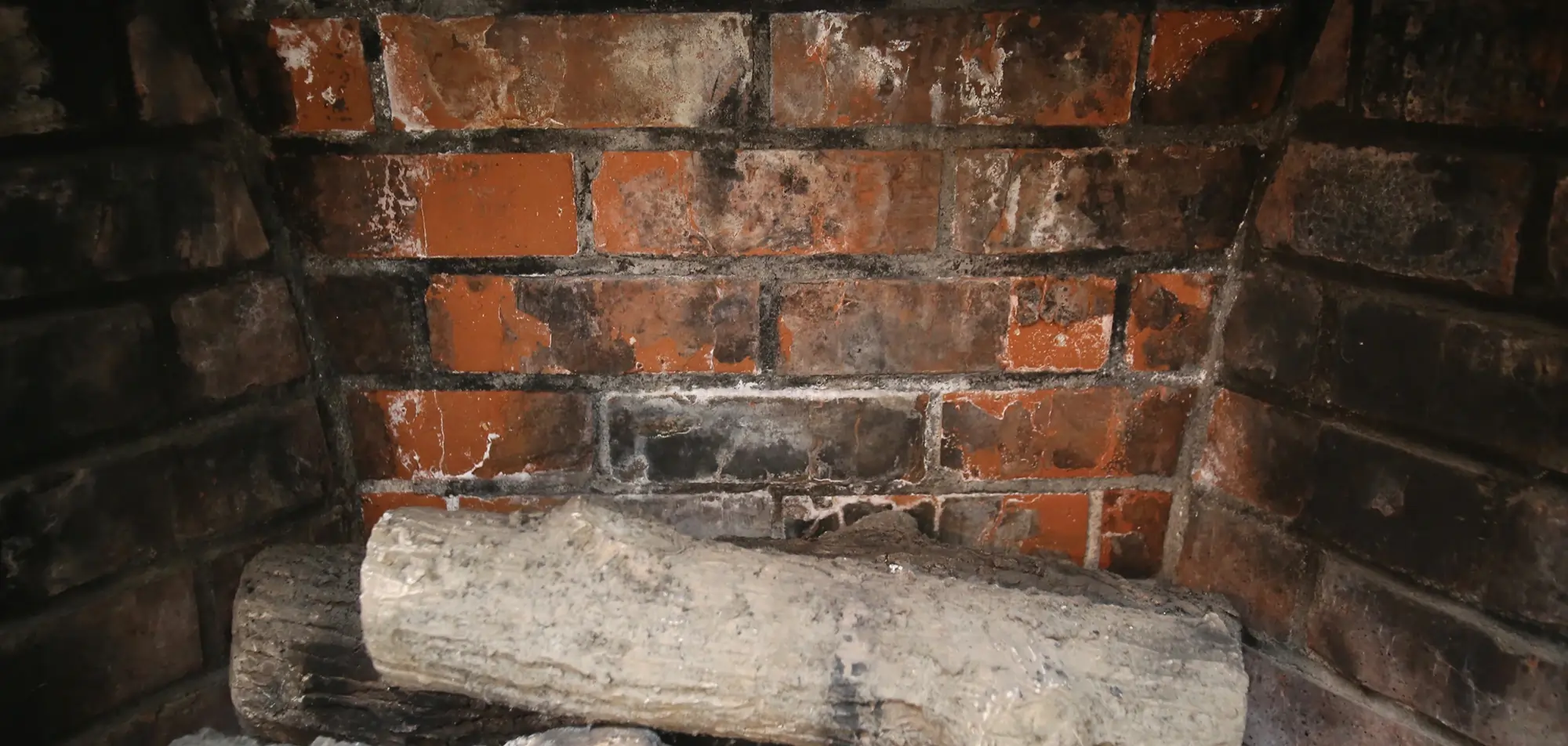 Close-up of firebox masonry showing damage requiring professional fireplace repair