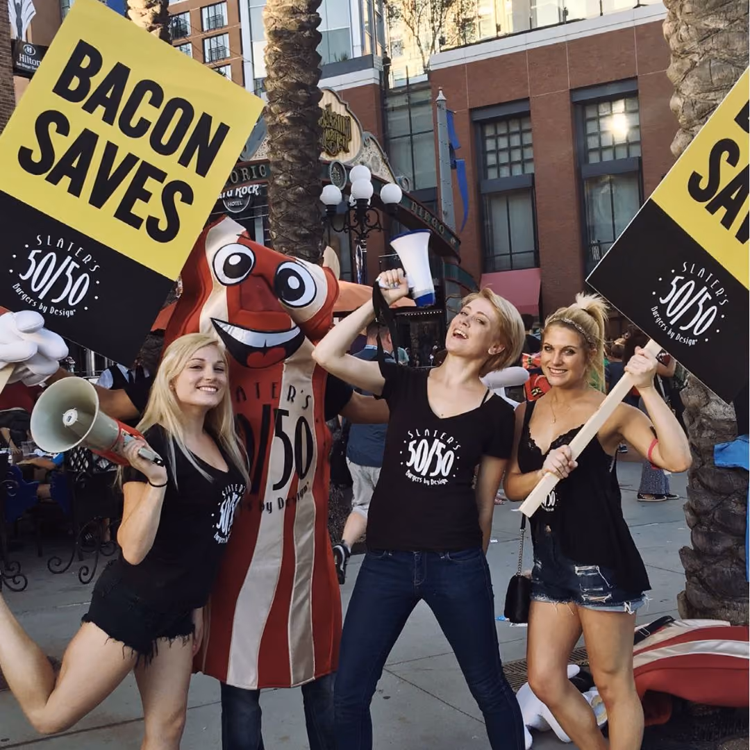 Girls holding Bacon Saves Sign