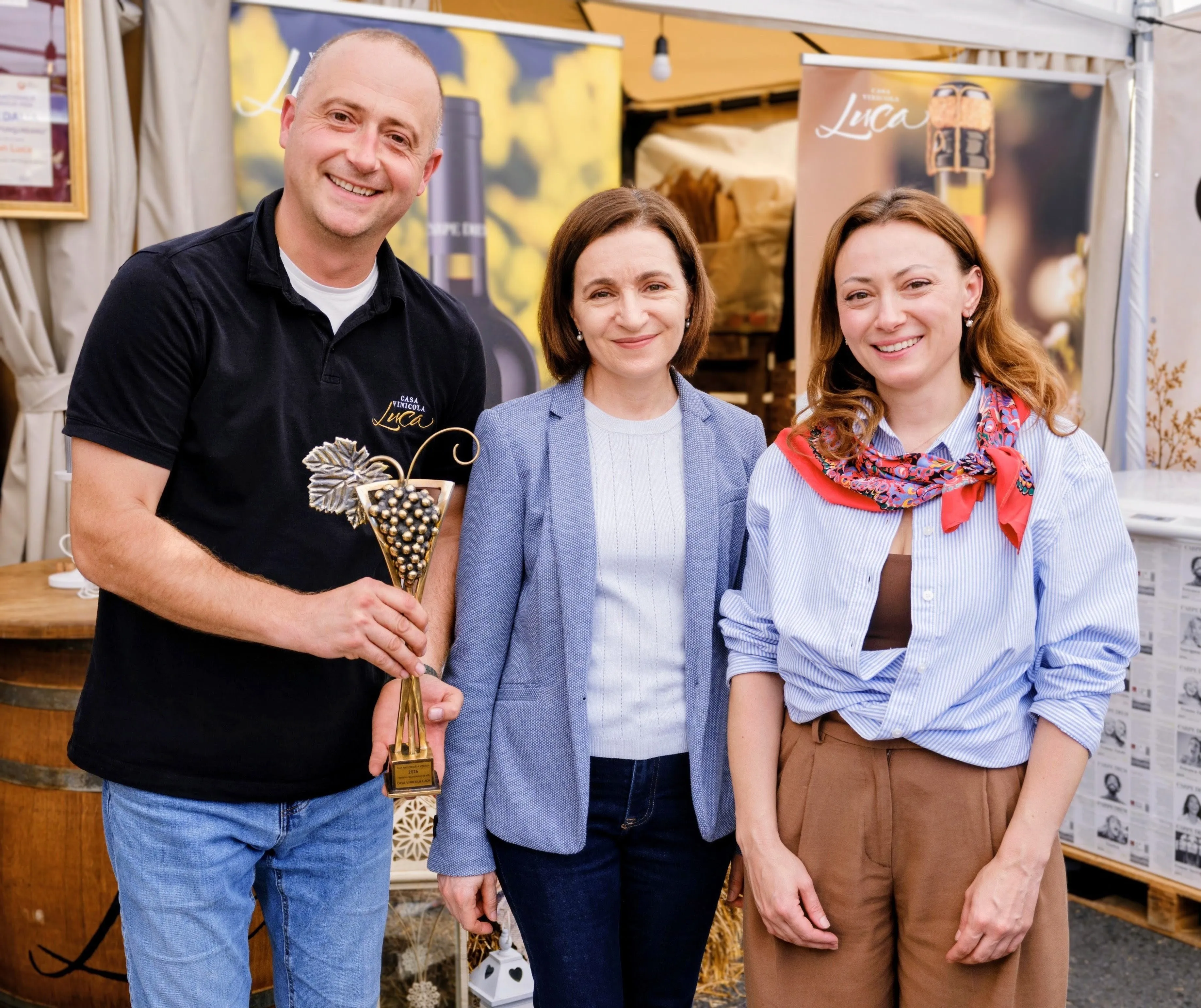Ion Luca Jr., President Maia Sandu and Natalia Gangura with the Creatorul Vinului 2026 trophy at the Casa Vinicola Luca stand