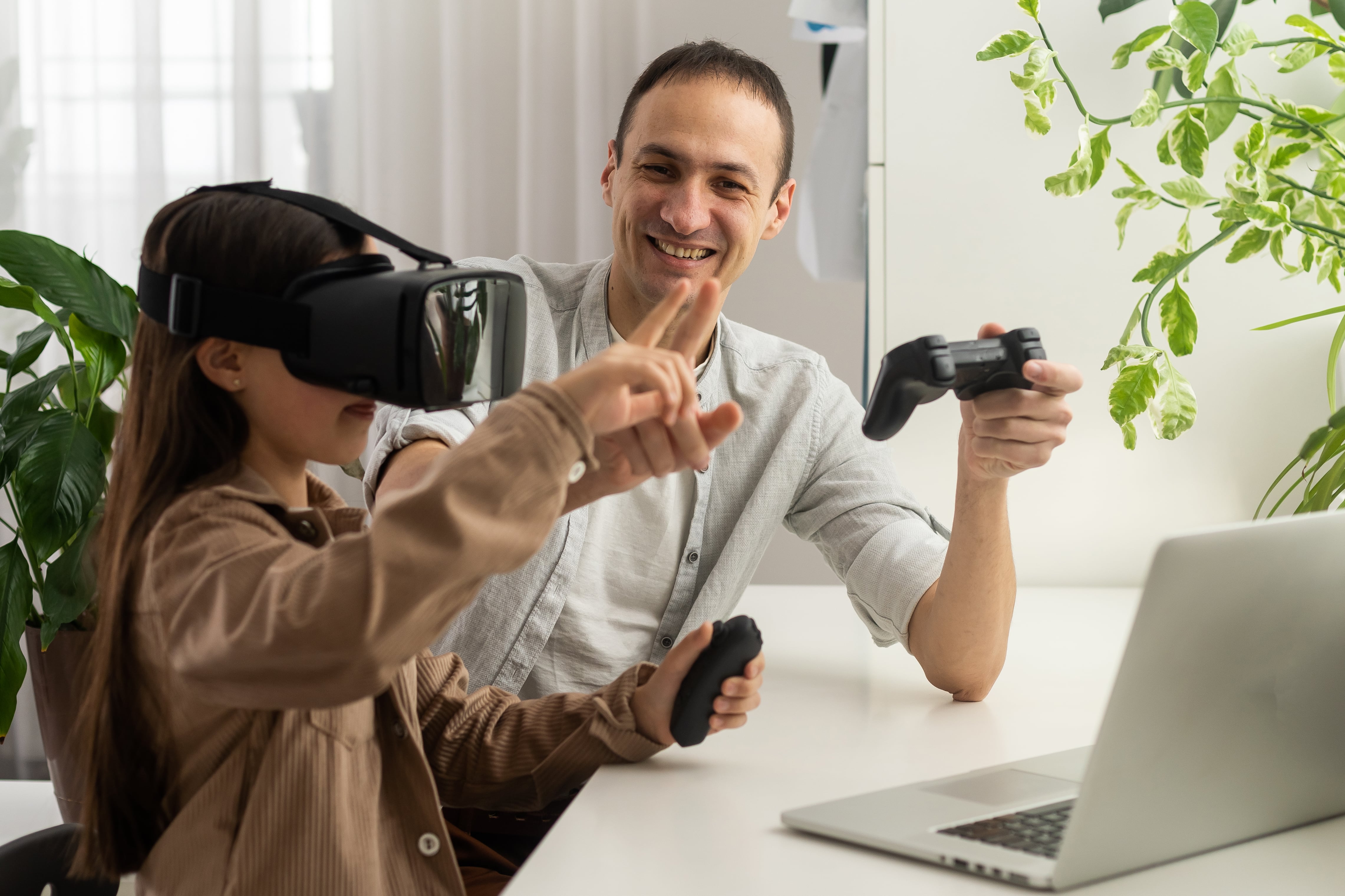 Dziewczynka w goglach VR korzysta z wirtualnej rzeczywistości pod opieką rodzica.