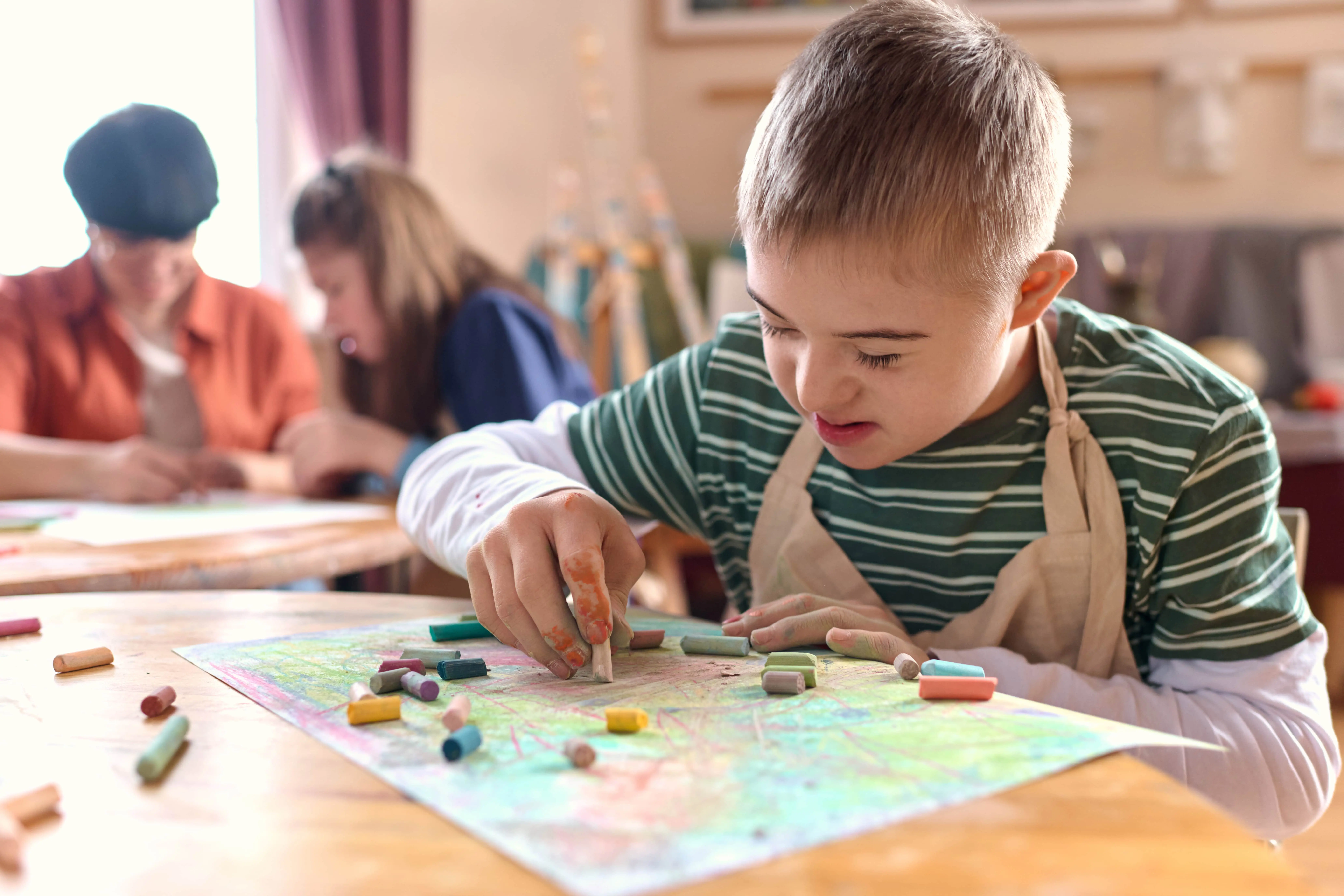 Dziecko ze specjalnymi potrzebami edukacyjnymi (SPE) podczas zajęć arteterapii rysuje pastelami w szkole specjalnej – wspieranie emocji i rozwoju poprzez sztukę.