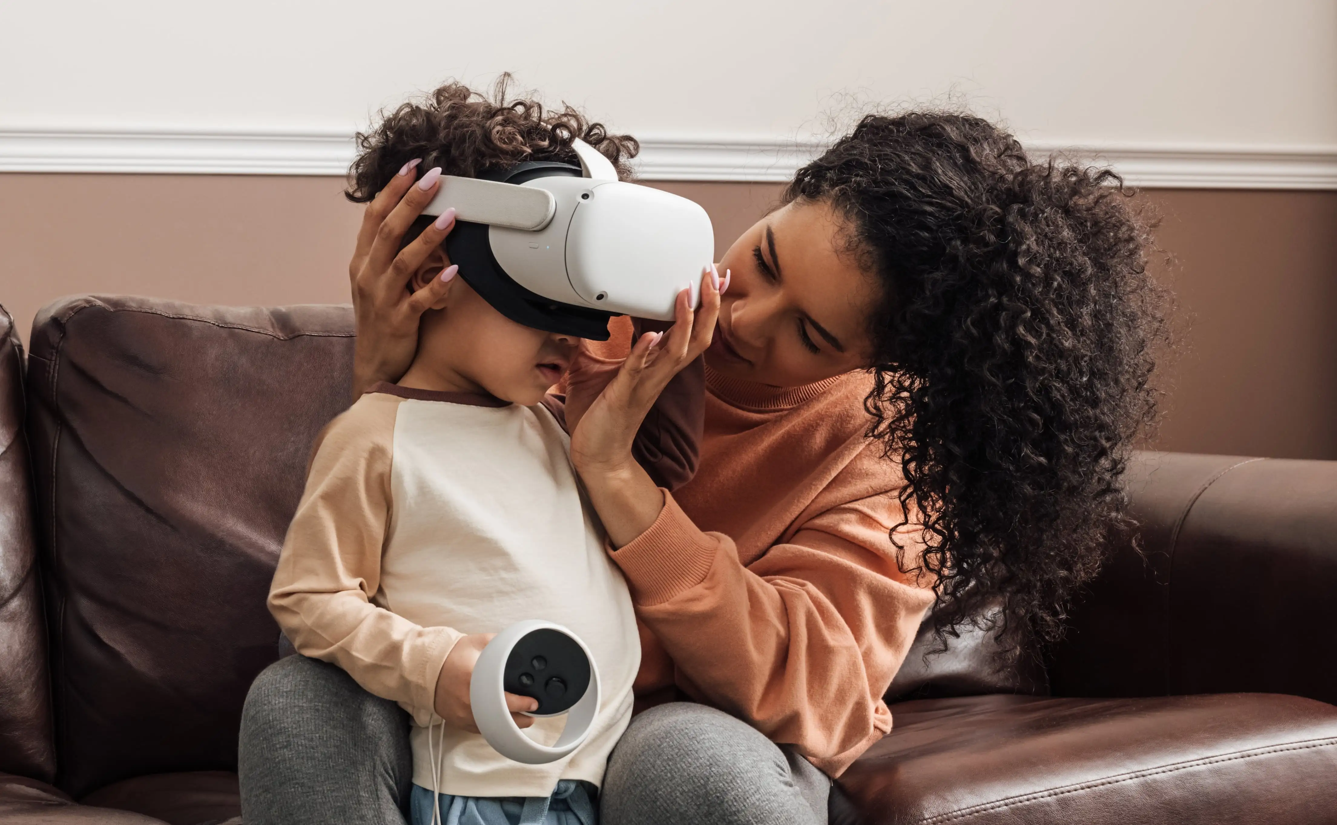 A mother helping her child put on VR goggles in a safe home environment, showing what responsible introduction to virtual reality looks like.