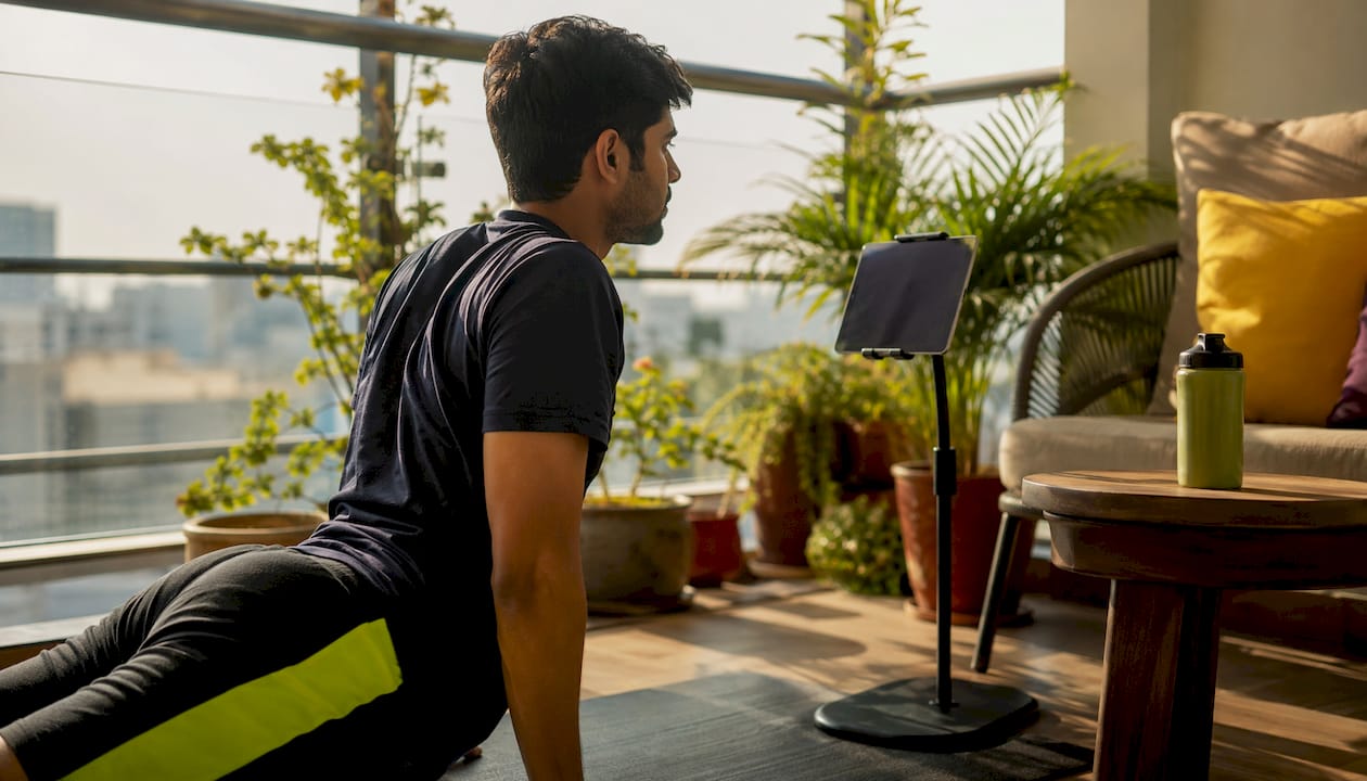 Man following online beginner yoga session at home
