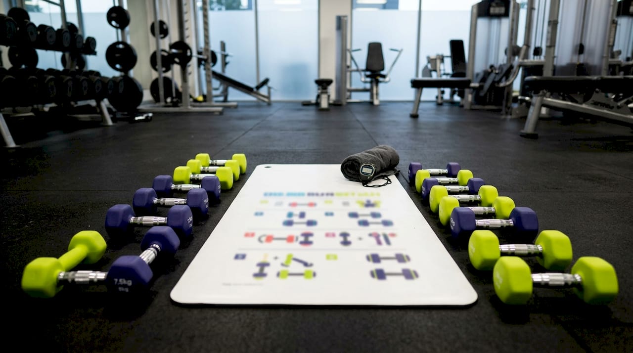 Flat lay of dumbbells and workout plan