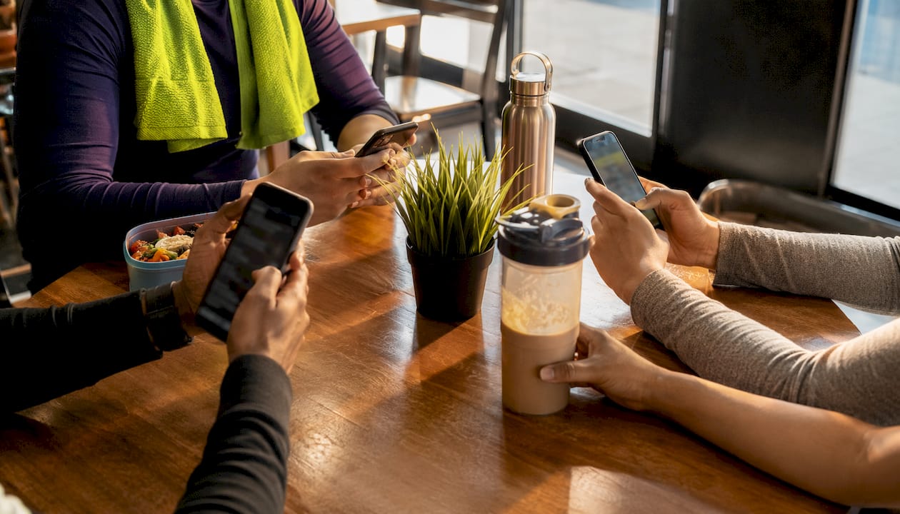 Hands holding phones with fitness app reviews