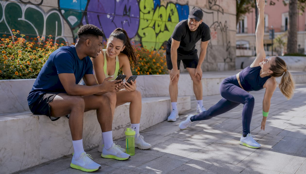 Diverse young adults sharing fitness app outdoors