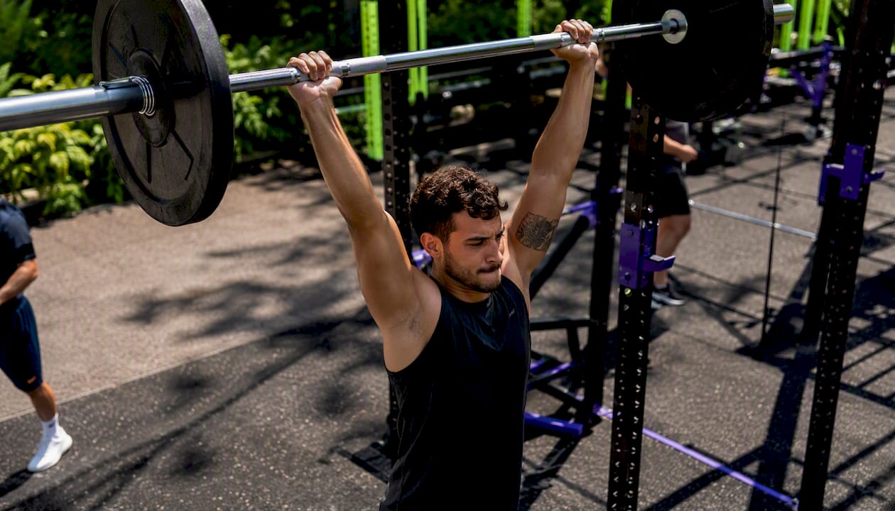 Man performing barbell bench press in gym