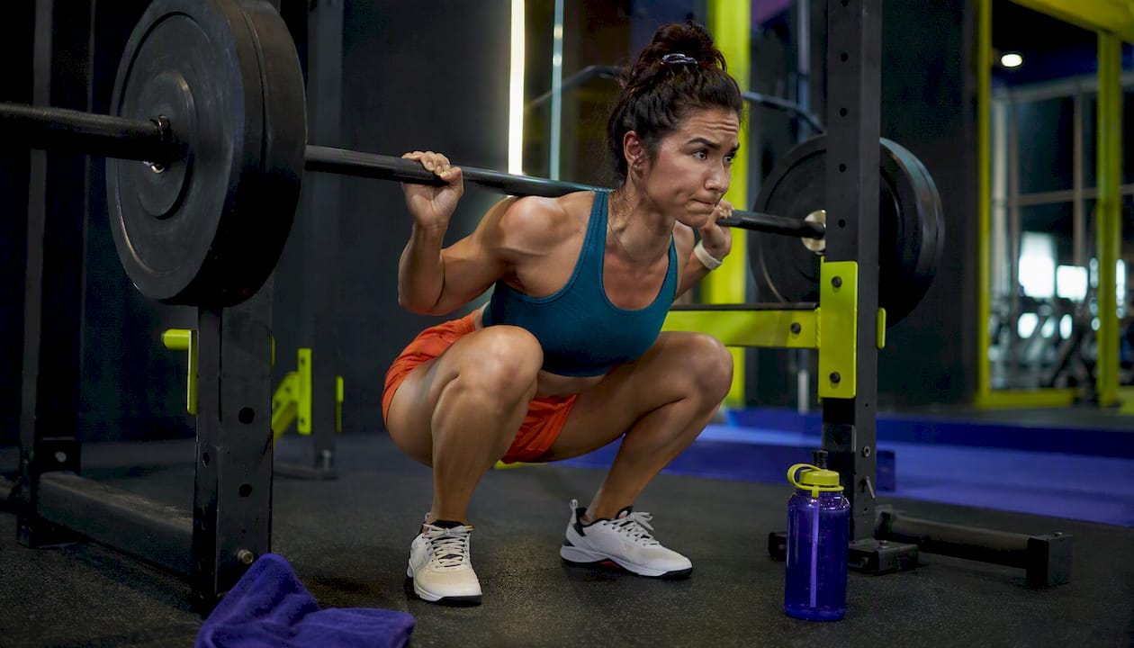 Person performing heavy barbell squat in gym