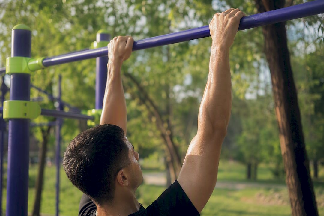 Hands gripping pull-up bar for dead hang