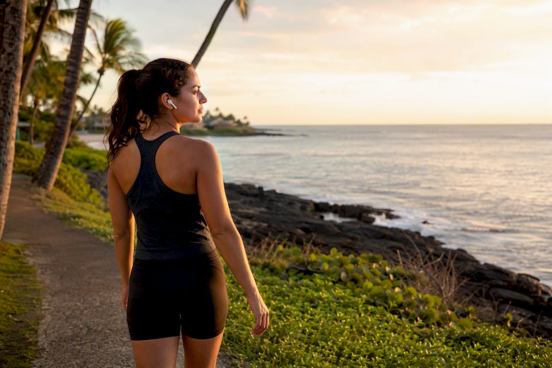 Young adult walking briskly outdoors with earbuds