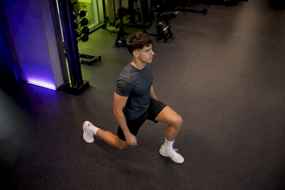 Young adult doing walking lunges in gym