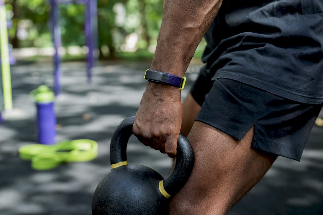 Fitness tracker on wrist with gym equipment