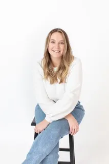 Former PY intern Maddie Rafferty sits on a stool against a white background
