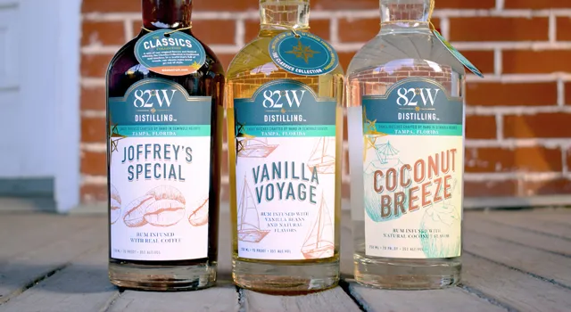 Three rum bottles standing next to each other in front of a brick background