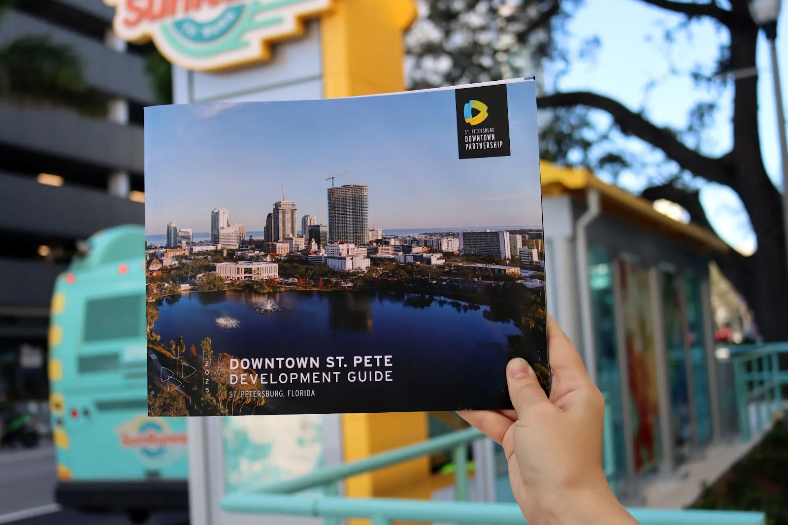 An image of the St. Petersburg Downtown Partnership Development Guide held up in front of the SunRunner bus