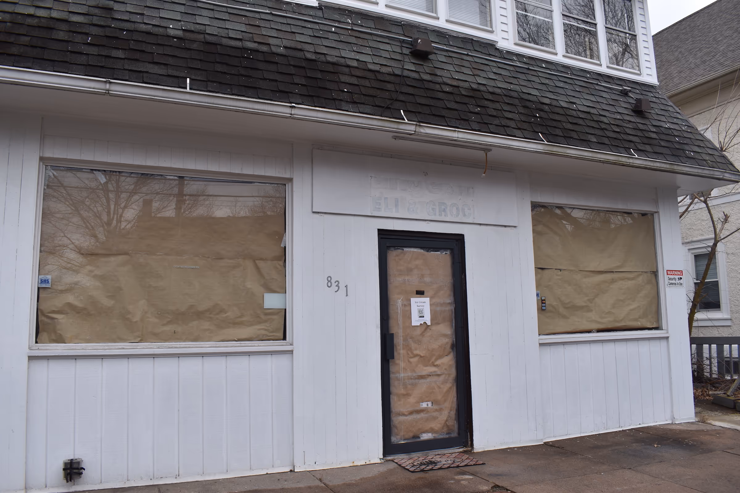 Abandoned storefront: A white wooden building with papered-over windows and door. The address "831" is visible. The image shows the storefront before it was renovated into Elena's on Orange ice cream shop. Credit noted as from the New Haven Independent.