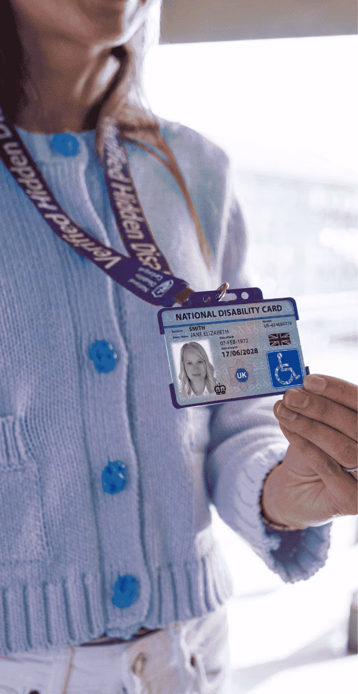 Photo of a woman in a wheelchair holding up her National Disability Card on its lanyard.