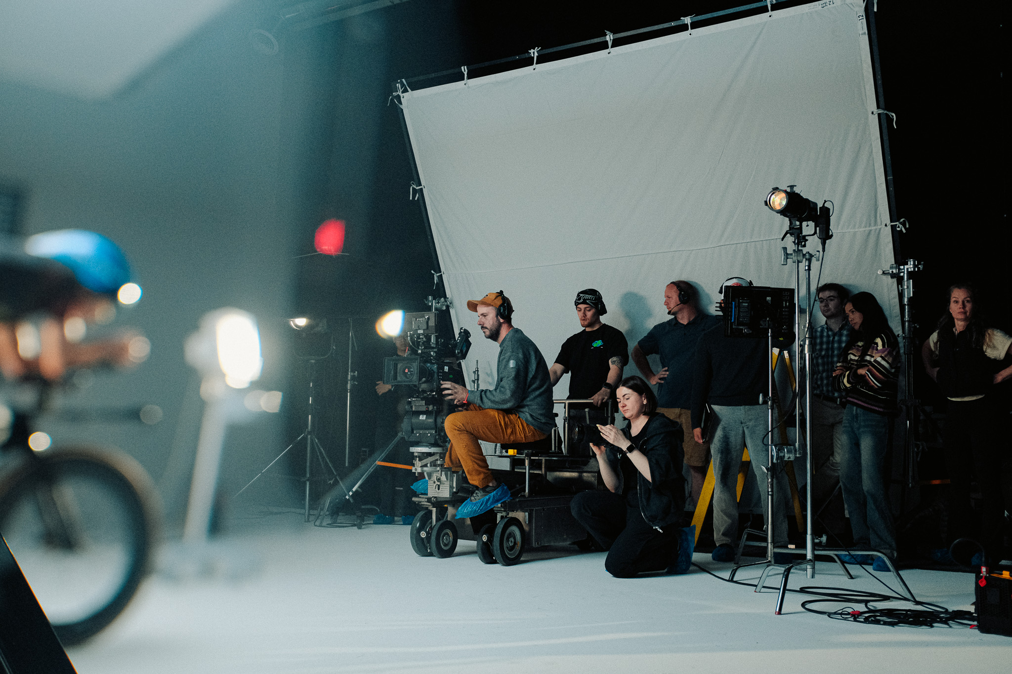 Crew watching from beside the camera dolly on the cyc wall set at XVP while the cyclist rides in the foreground