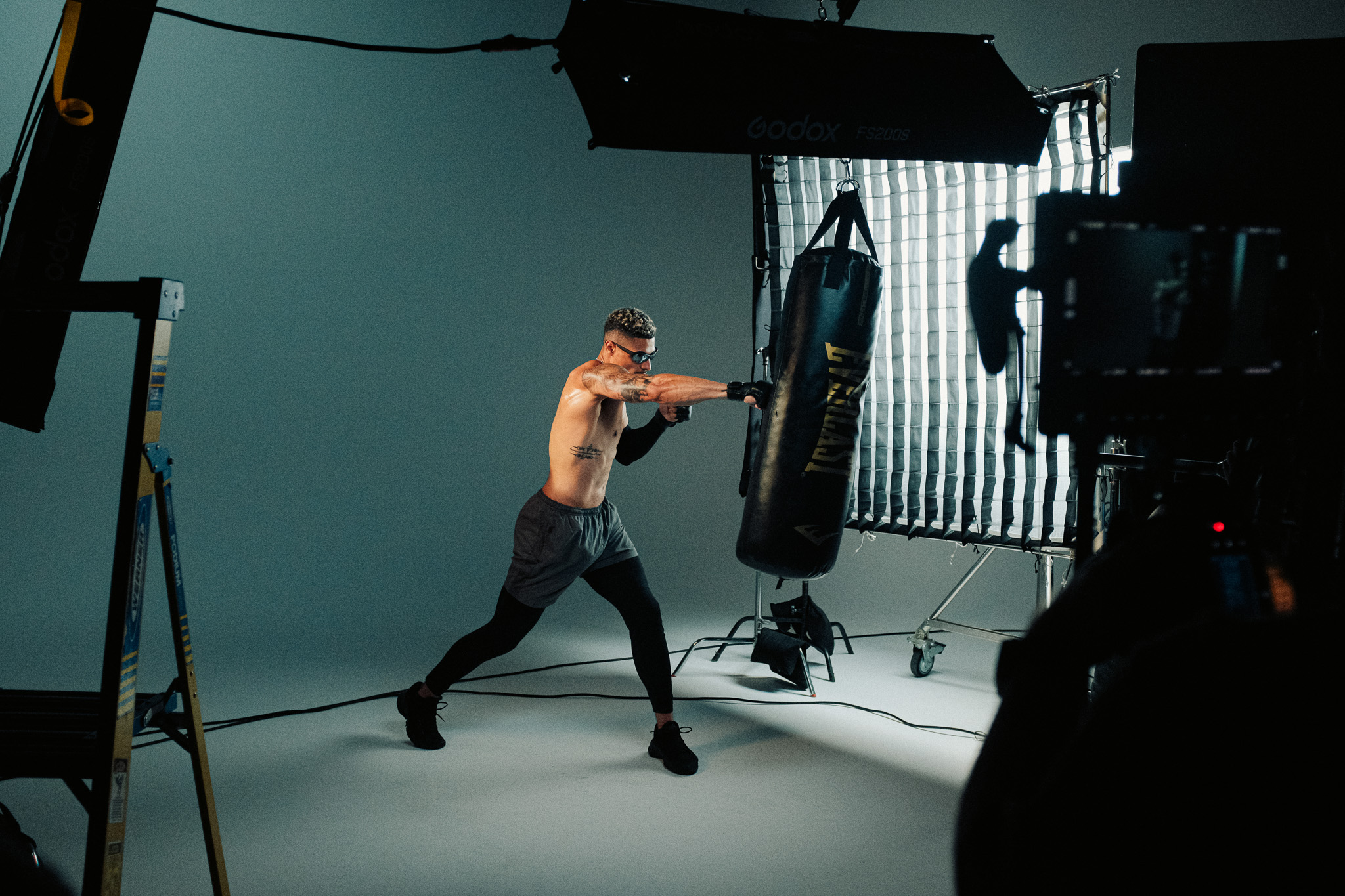 Jordan throwing a punch at the heavy bag under a large overhead softbox